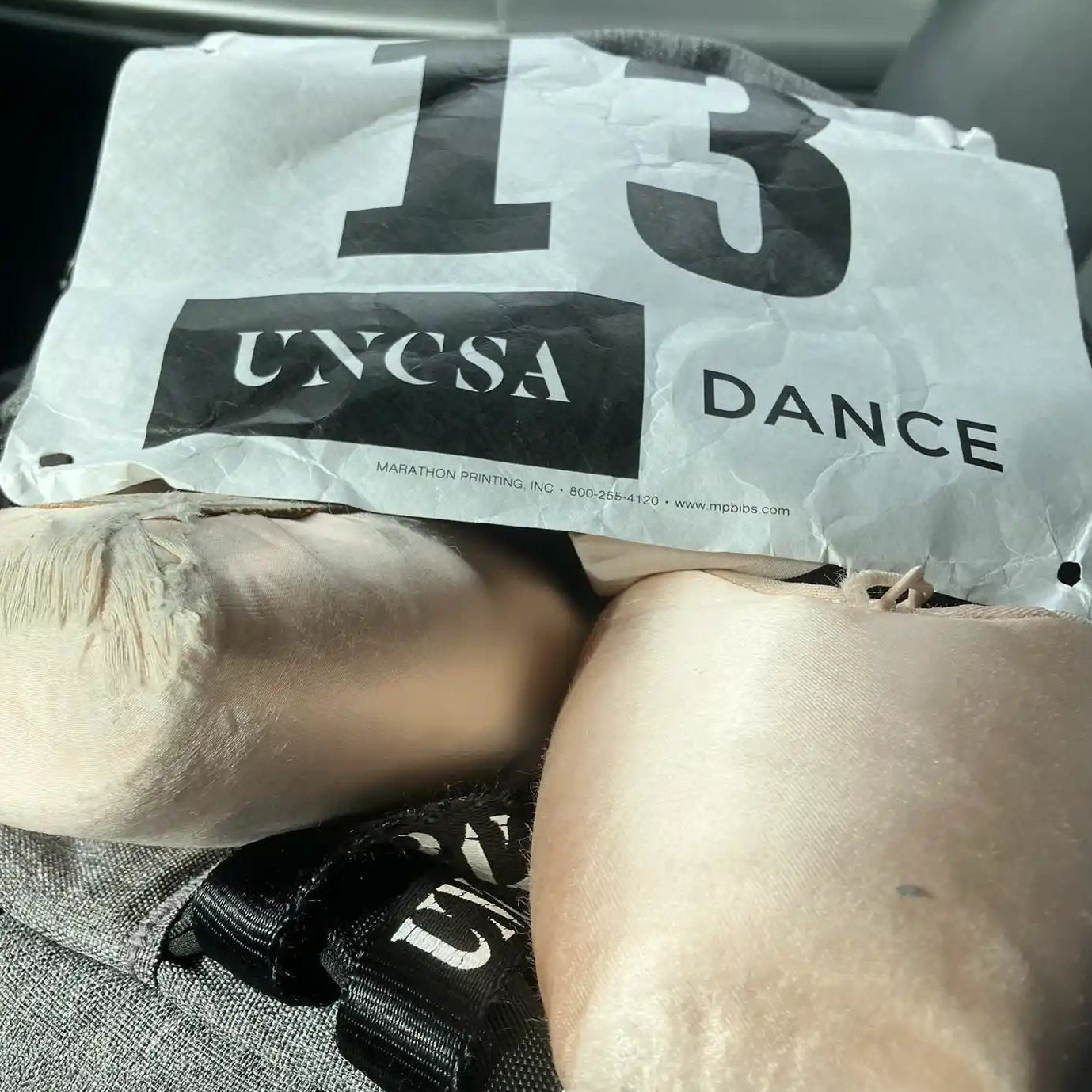 Ballet audition number sitting on top of a pair of pointe shoes